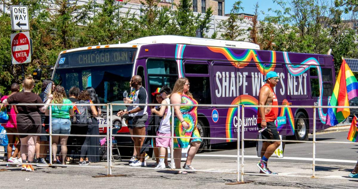 The wrapped Columbia Pride bus parked along the parade route as a cooling station, with a crowd gathered at its front door